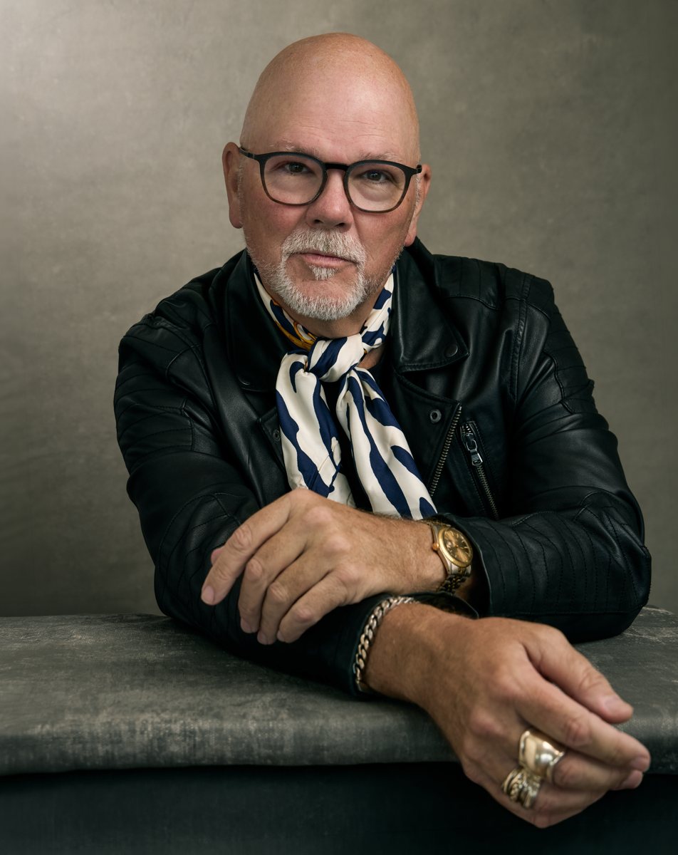 Gary Waddell in a black leather jacket and navy-and-cream scarf, looking directly at the camera